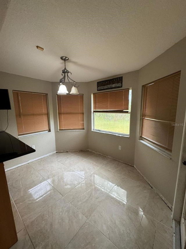 unfurnished dining area featuring a textured ceiling and a notable chandelier