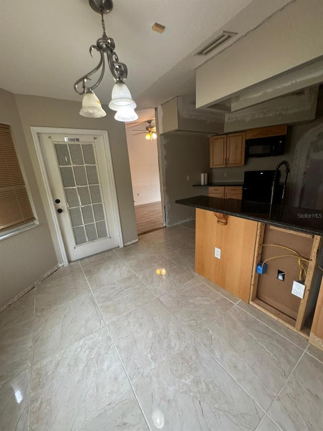 kitchen featuring ceiling fan with notable chandelier, kitchen peninsula, black appliances, hanging light fixtures, and a breakfast bar