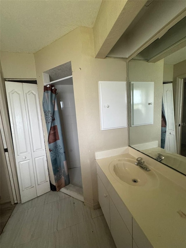 bathroom featuring walk in shower, vanity, and a textured ceiling