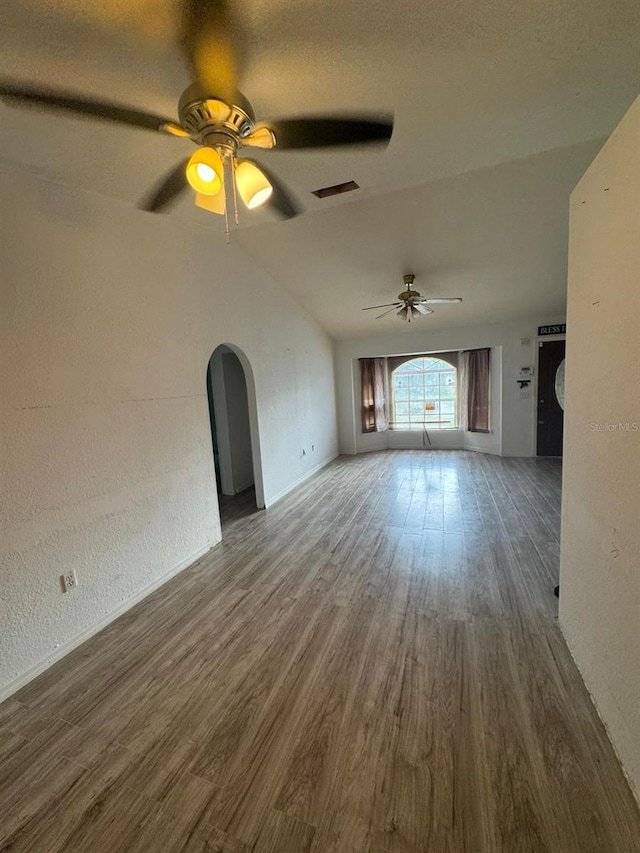 unfurnished living room with ceiling fan, dark hardwood / wood-style floors, and vaulted ceiling