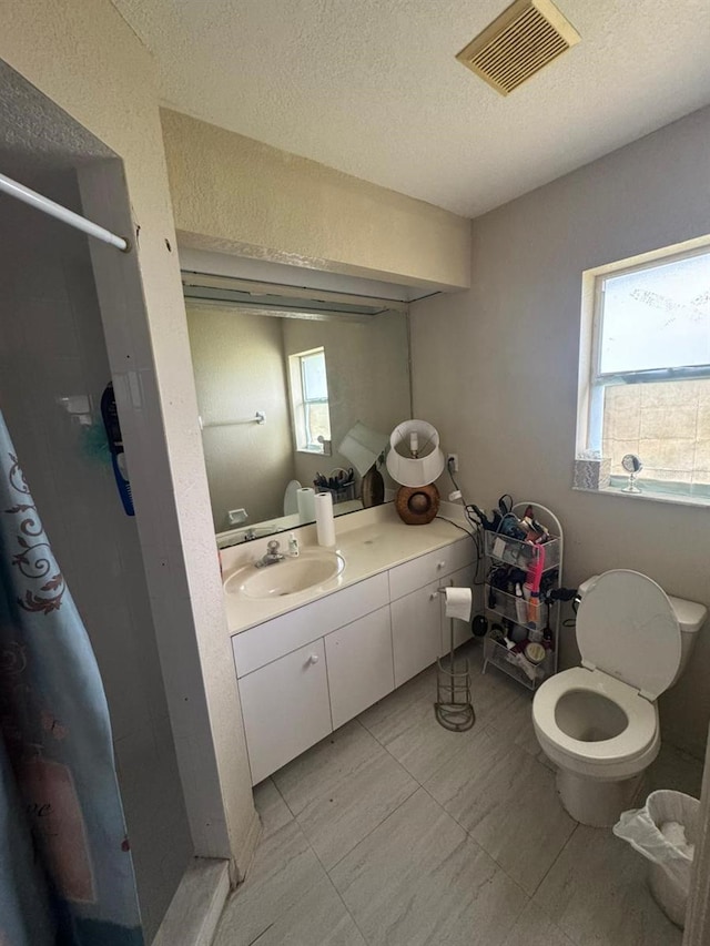 bathroom with walk in shower, vanity, a textured ceiling, and plenty of natural light