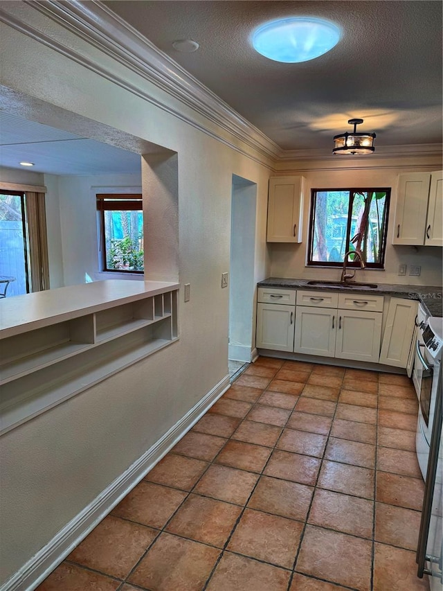 kitchen featuring sink, a textured ceiling, ornamental molding, white cabinets, and range