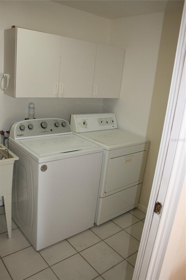 washroom featuring washing machine and dryer, cabinets, and light tile patterned floors