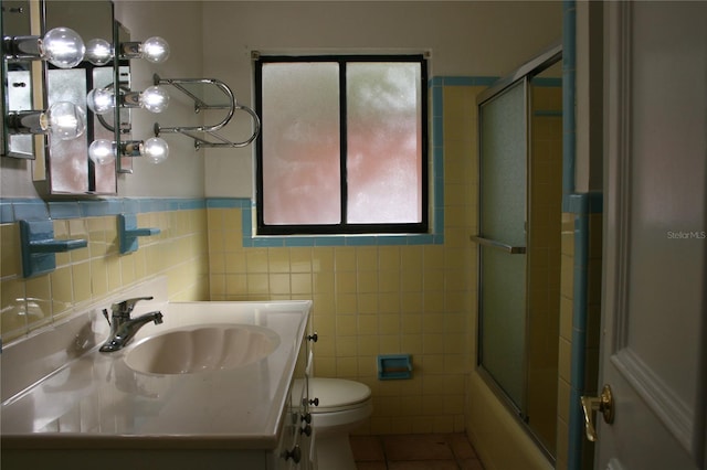 full bathroom featuring enclosed tub / shower combo, tile patterned flooring, vanity, tile walls, and toilet