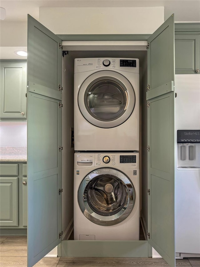 laundry area with light wood-type flooring and stacked washer / drying machine