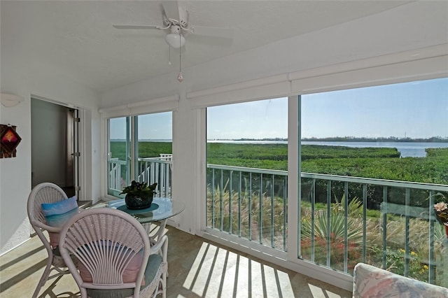 sunroom / solarium featuring plenty of natural light, a water view, and ceiling fan