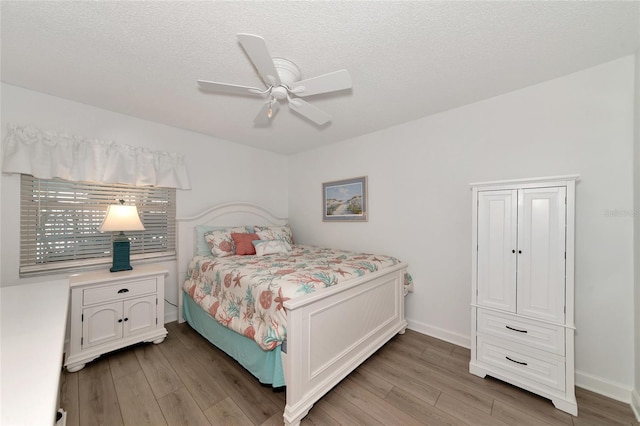 bedroom with hardwood / wood-style floors, ceiling fan, and a textured ceiling