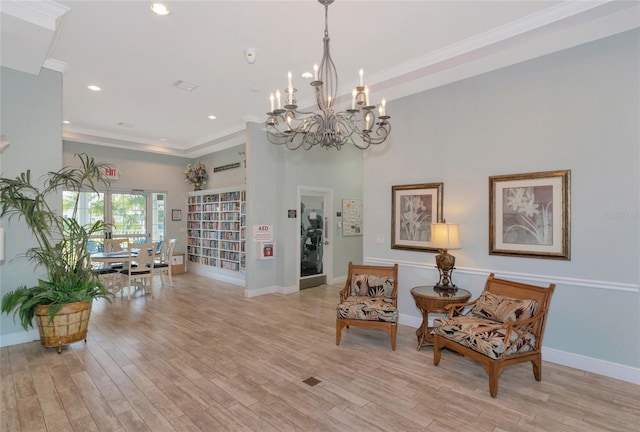 living area featuring light wood-type flooring, a notable chandelier, and crown molding