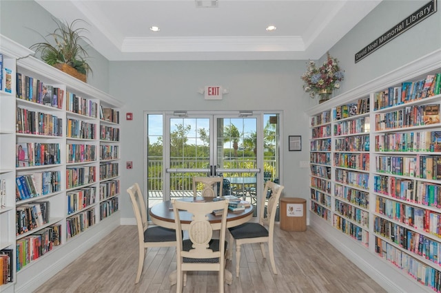 dining area featuring a raised ceiling, light wood-type flooring, and crown molding