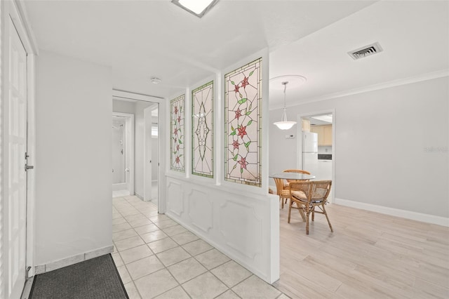 hallway with light hardwood / wood-style flooring and crown molding