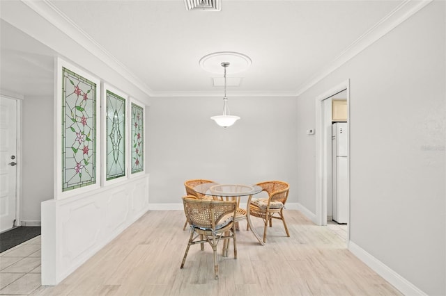 dining space featuring light hardwood / wood-style floors and crown molding