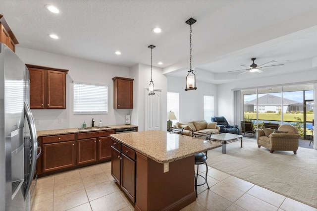 kitchen with sink, a breakfast bar, light tile patterned floors, a kitchen island, and stainless steel fridge with ice dispenser