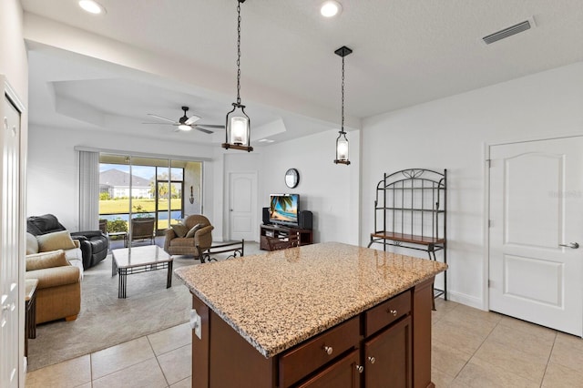 kitchen featuring light stone countertops, ceiling fan, dark brown cabinets, light colored carpet, and pendant lighting