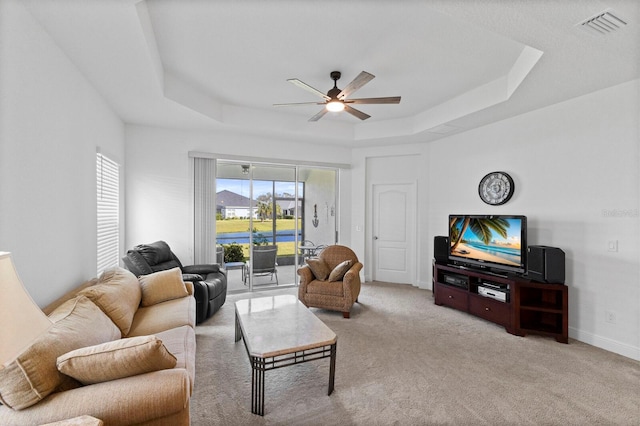 living room with light carpet, ceiling fan, and a raised ceiling