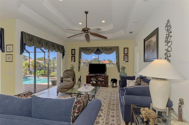 tiled living room featuring ceiling fan, crown molding, and a tray ceiling