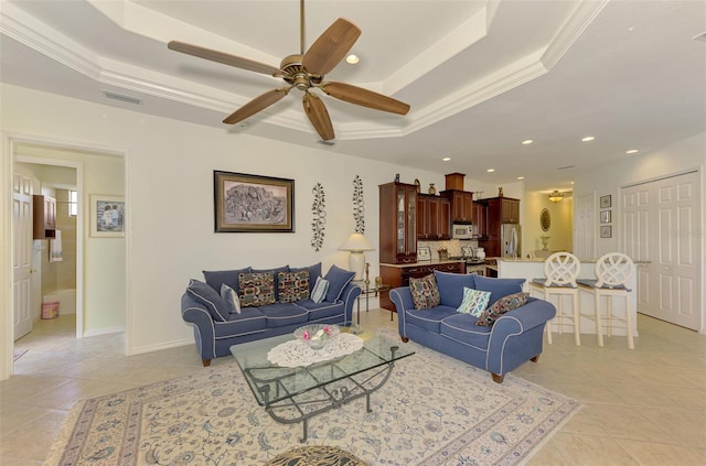 tiled living room featuring a tray ceiling, ceiling fan, and crown molding