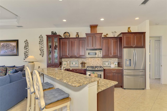 kitchen featuring a kitchen breakfast bar, stainless steel appliances, light stone counters, and backsplash