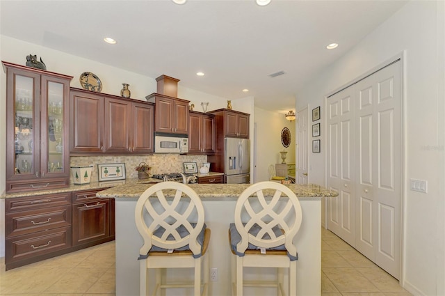 kitchen featuring light stone counters, a breakfast bar area, a kitchen island, and stainless steel fridge