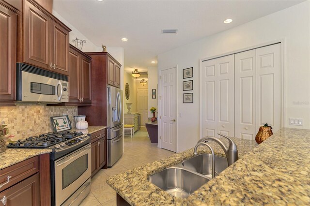 1509 Raphis Royale Blvd, Englewood, FL 34223 - kitchen featuring appliances with stainless steel finishes, a sink, light tile patterned flooring, backsplash, and light stone counters