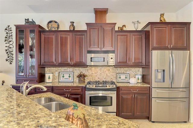 kitchen featuring tasteful backsplash, appliances with stainless steel finishes, light tile patterned floors, light stone countertops, and sink