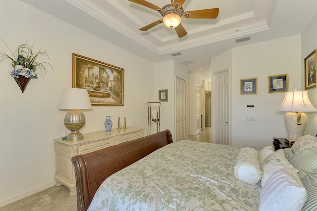 bedroom with ornamental molding, light carpet, ceiling fan, and a tray ceiling