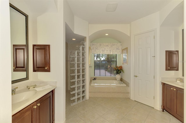 bathroom featuring vanity, tile patterned flooring, and a relaxing tiled tub