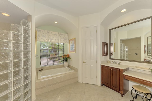 bathroom with tiled bath, tile patterned flooring, and vanity