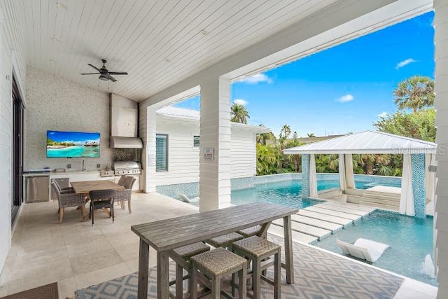 view of patio featuring exterior kitchen, ceiling fan, pool water feature, and grilling area