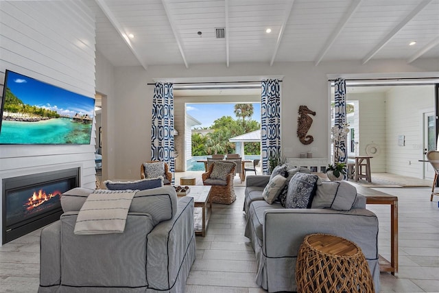 living room with plenty of natural light, light hardwood / wood-style flooring, and beamed ceiling