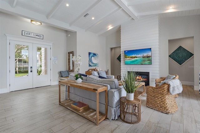 living room featuring french doors, beamed ceiling, a large fireplace, light wood-type flooring, and high vaulted ceiling