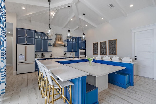 kitchen featuring premium range hood, a large island, appliances with stainless steel finishes, blue cabinetry, and light hardwood / wood-style flooring