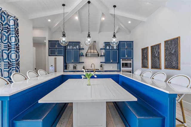 kitchen featuring a kitchen bar, blue cabinetry, high quality fridge, a kitchen island, and beam ceiling