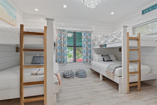 bedroom with wood walls, an inviting chandelier, and wood-type flooring