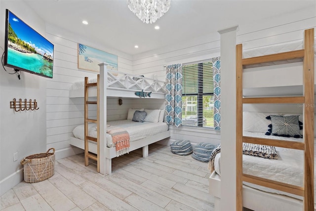 bedroom featuring wooden walls, a chandelier, and hardwood / wood-style floors