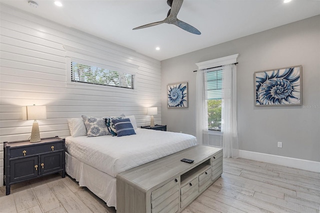 bedroom featuring ceiling fan, wood walls, and light hardwood / wood-style floors