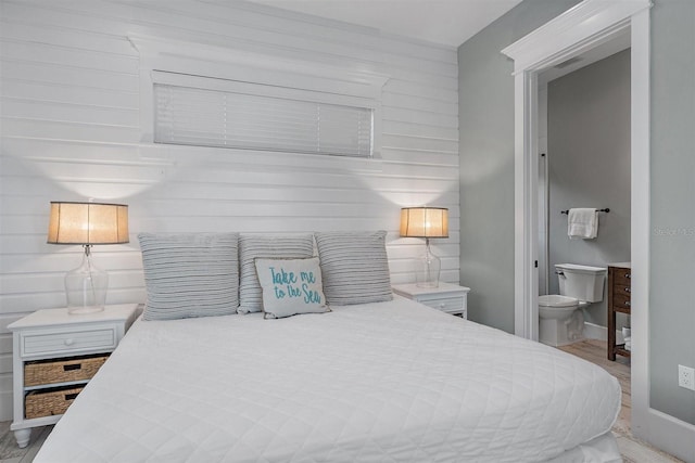 bedroom with connected bathroom and light hardwood / wood-style flooring