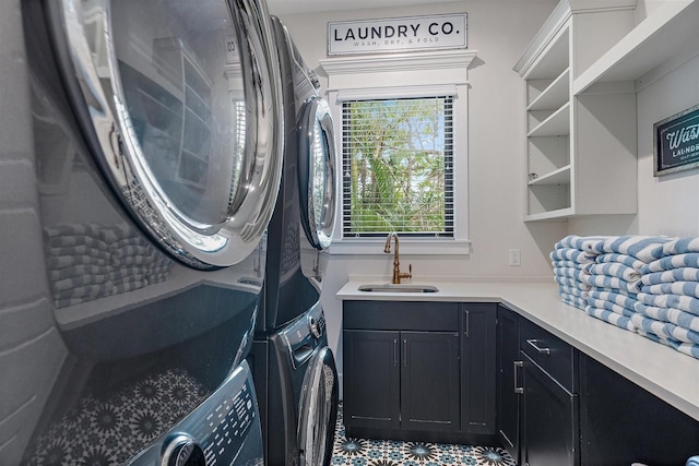 clothes washing area featuring sink, stacked washer and clothes dryer, and cabinets