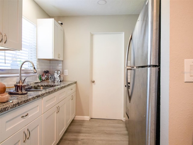 kitchen featuring light hardwood / wood-style floors, white cabinetry, sink, light stone counters, and stainless steel fridge