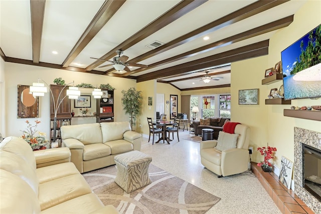 living room featuring beamed ceiling, ceiling fan, and a fireplace