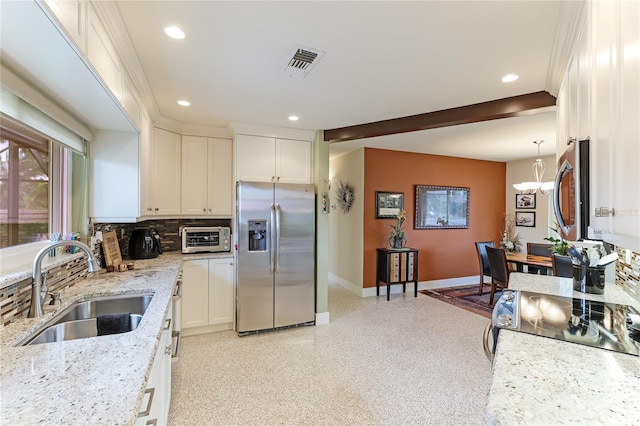 kitchen with white cabinetry, sink, light stone counters, appliances with stainless steel finishes, and hanging light fixtures