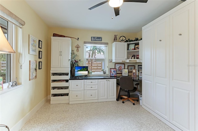 home office with a healthy amount of sunlight, built in desk, and ceiling fan