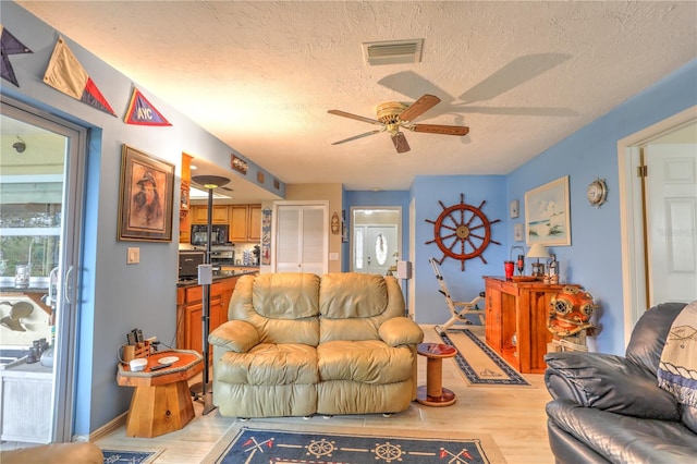 living room with light wood-type flooring, a textured ceiling, and ceiling fan