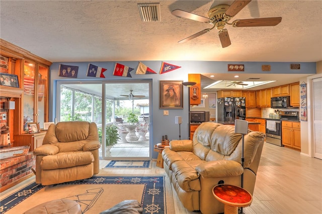 living room with light hardwood / wood-style floors, ceiling fan, and a textured ceiling