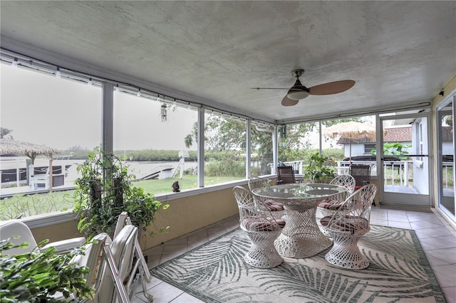 sunroom / solarium featuring a water view and ceiling fan