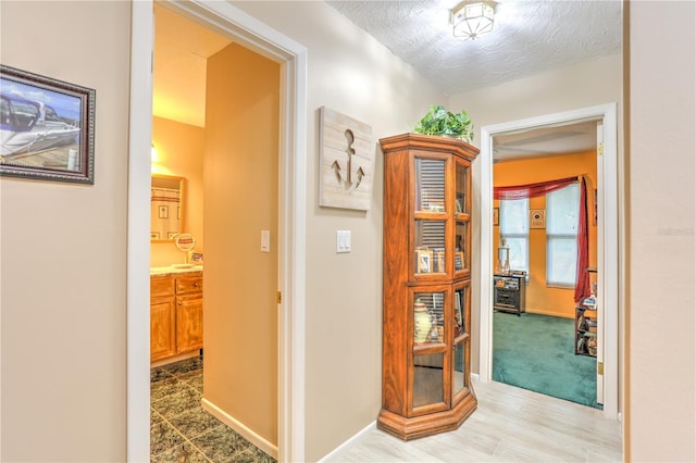 hallway featuring a textured ceiling and light hardwood / wood-style floors