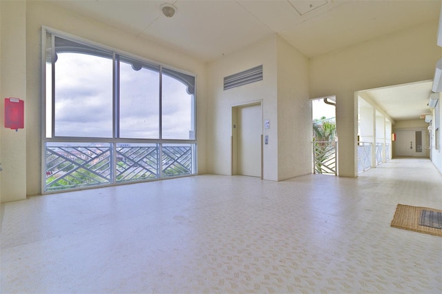 unfurnished room featuring elevator and plenty of natural light