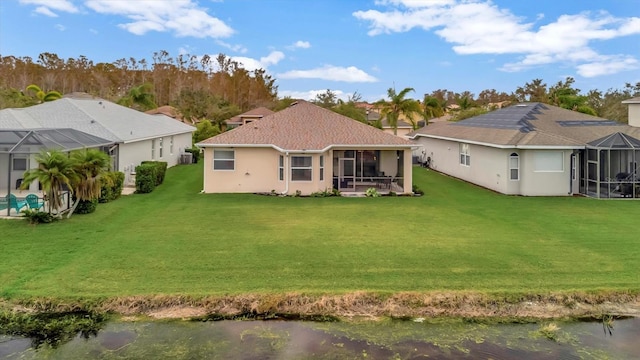 back of property with a sunroom, a lawn, a lanai, and a water view