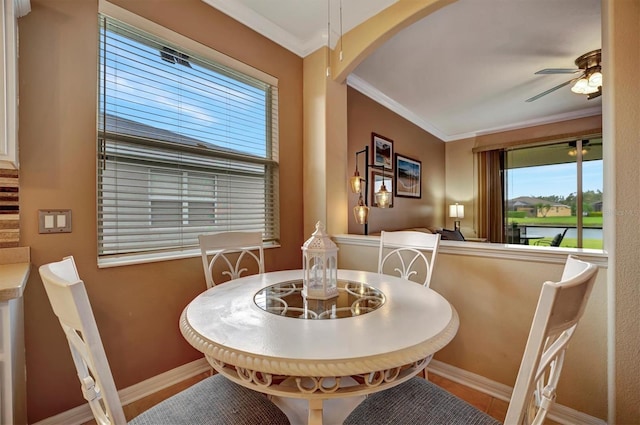 dining space with ornamental molding, a water view, and ceiling fan