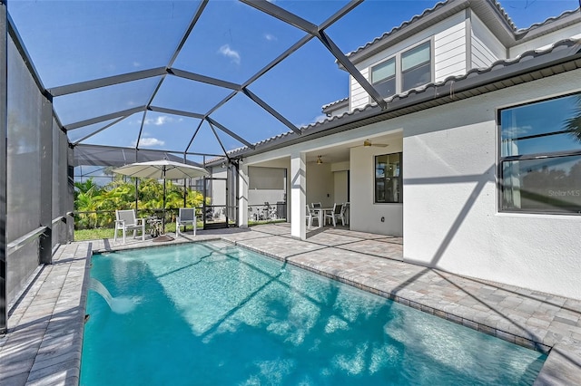 view of swimming pool with pool water feature, ceiling fan, a lanai, and a patio