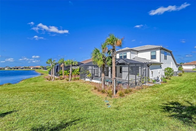 rear view of house featuring a yard, a water view, and glass enclosure